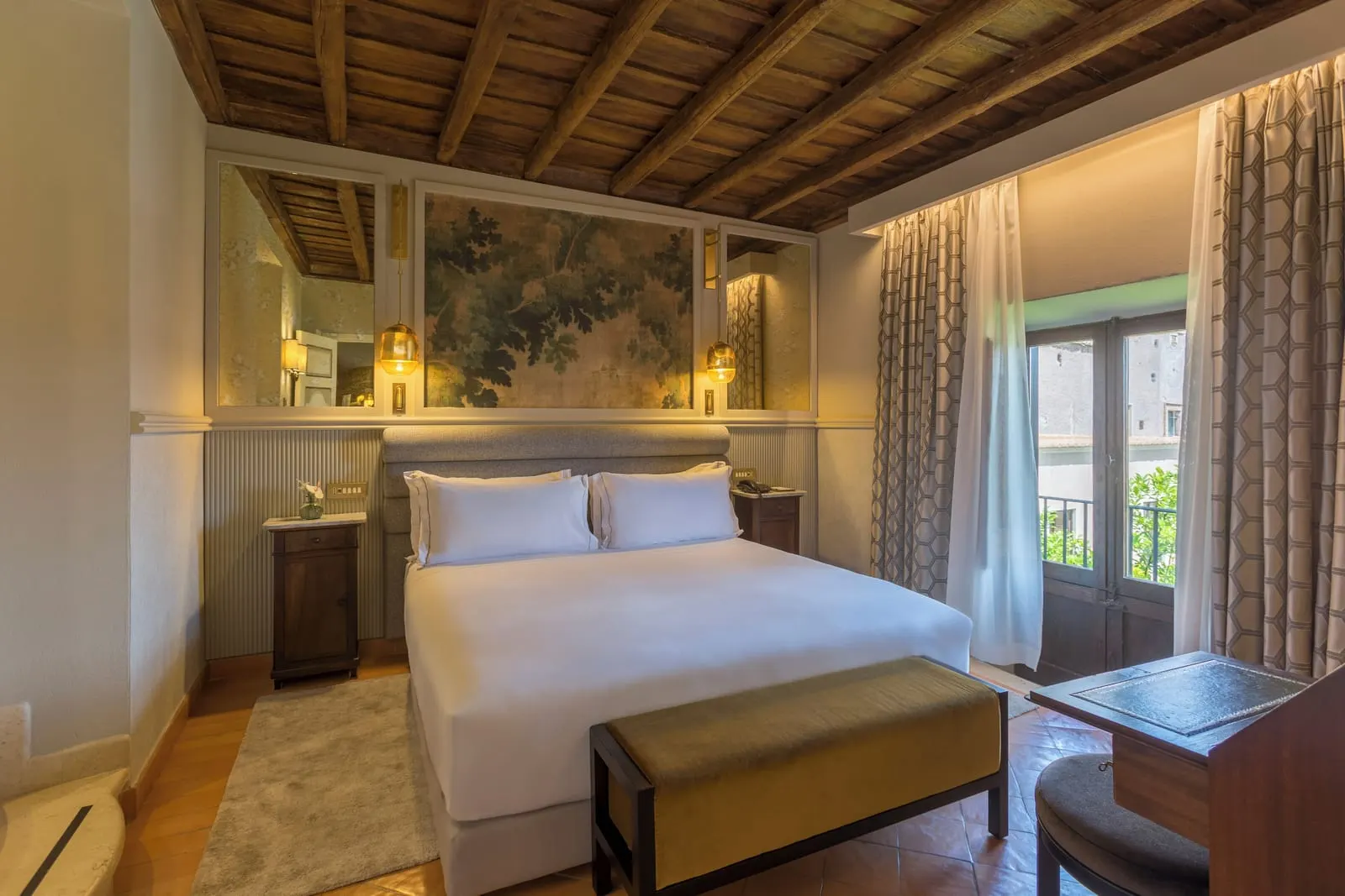 Garden Prestige at Donna Camilla Savelli: a bed with a bench under a beamed ceiling, the balcony door open onto trees