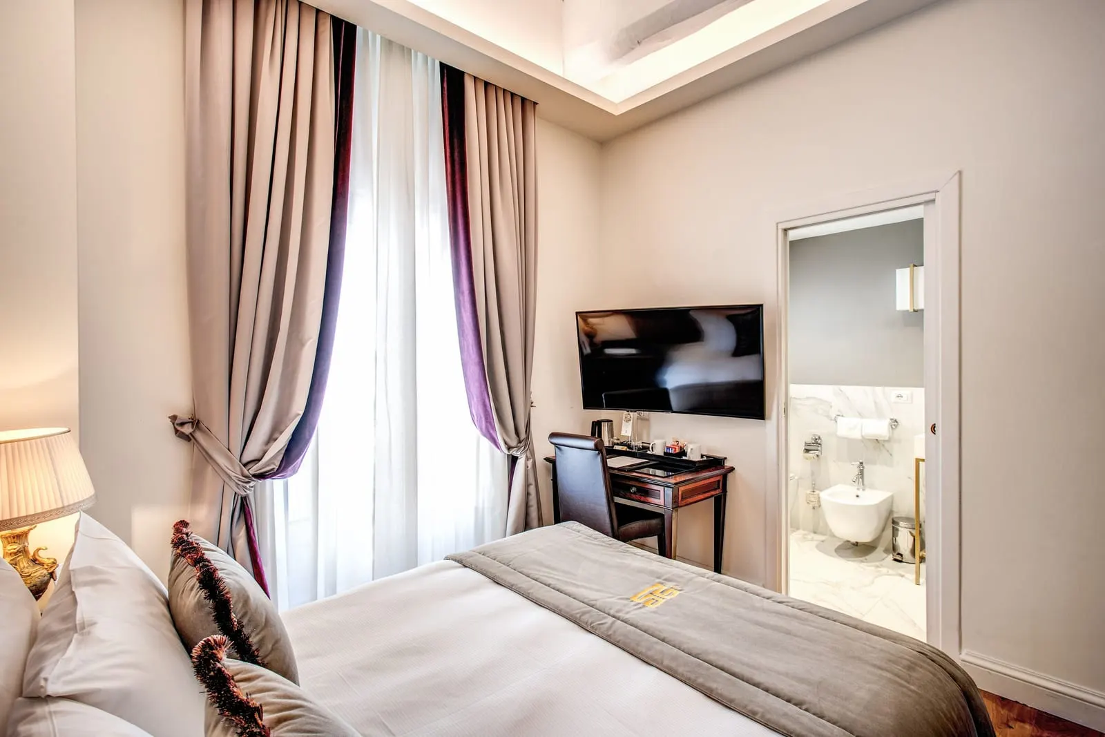 Single Room at Eitch Borromini Palazzo Pamphilj: the bed, a writing desk and a TV, with the bathroom door open