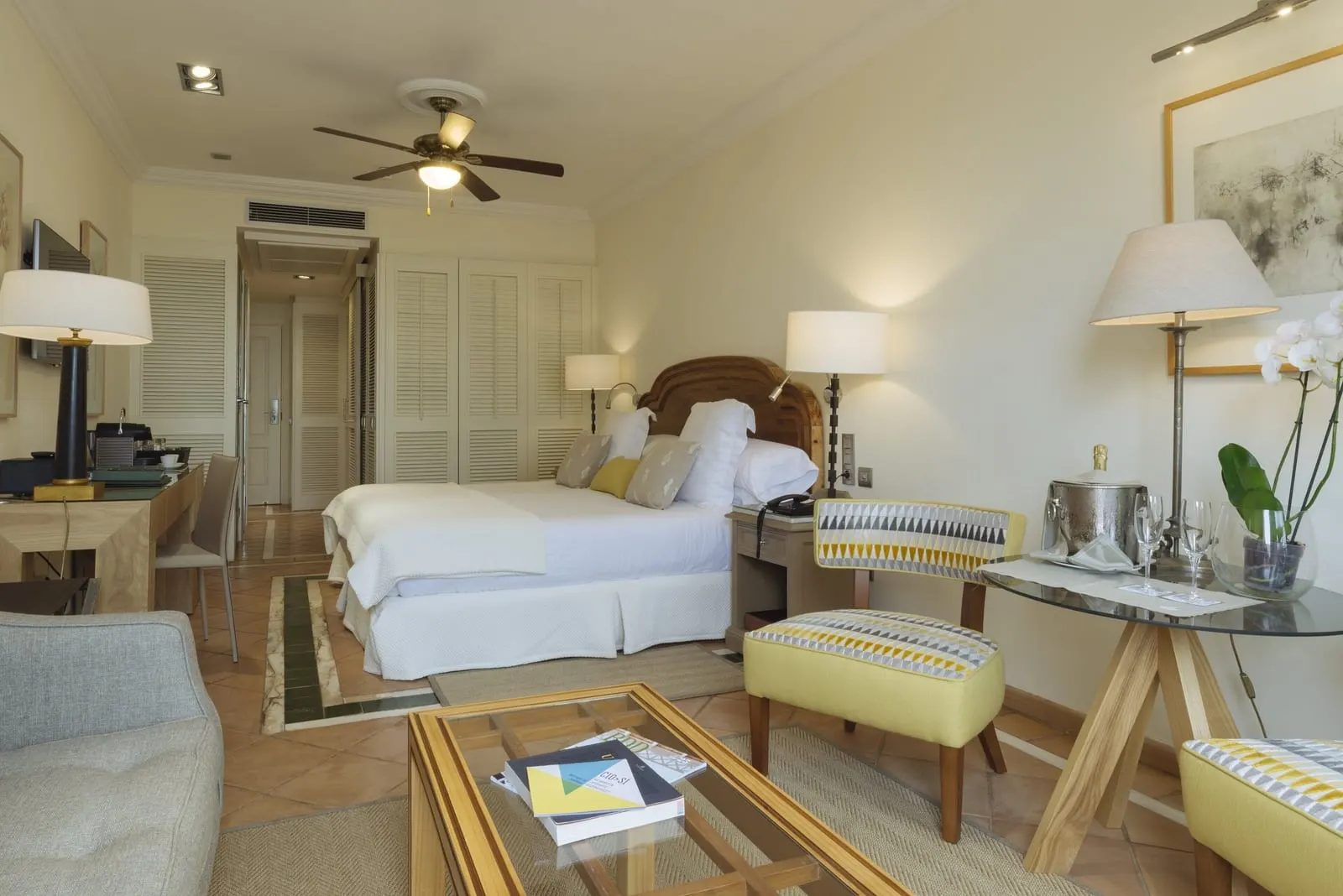 Casas Ducales Double Room at Bahía del Duque: the bed, a desk, a glass coffee table and two yellow stools