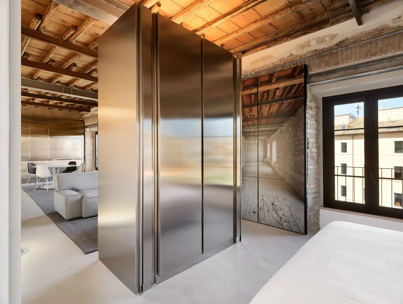 Suite Apartment Double at Rhinoceros Roma: the bed beside a steel wardrobe, with the sitting room beyond