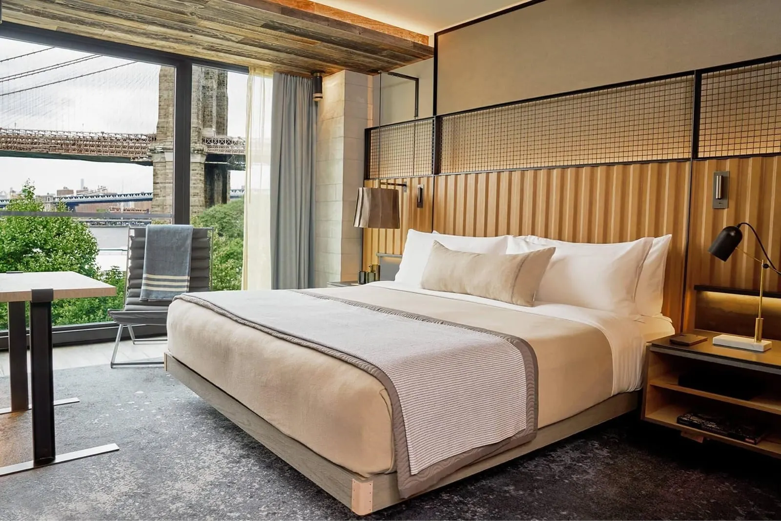 Bridge Studio Suite im 1 Hotel Brooklyn Bridge: ein Kingsize-Bett neben einem raumhohen Fenster zur Brooklyn Bridge, mit dem Steinturm und den Kabeln der Brücke in greifbarer Nähe