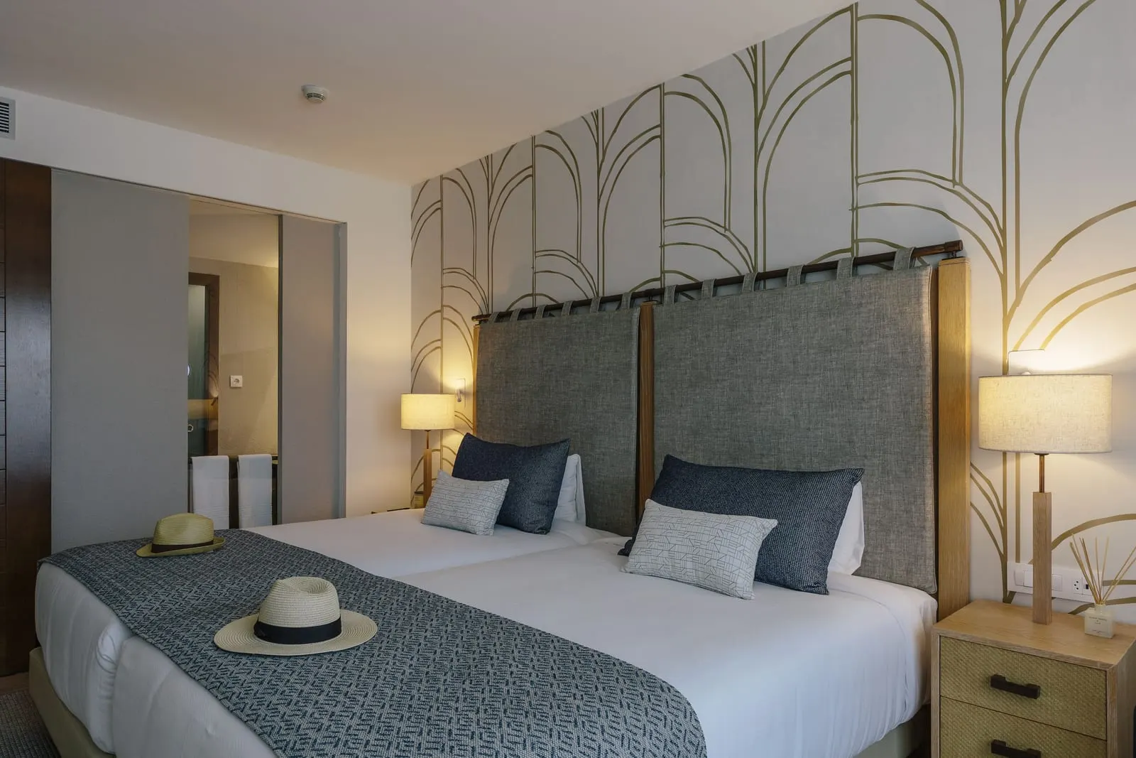 Preferred Club Double al Secrets Lanzarote Resort & Spa: un letto con un runner grigio, due lampade e una parete a testiera a motivi