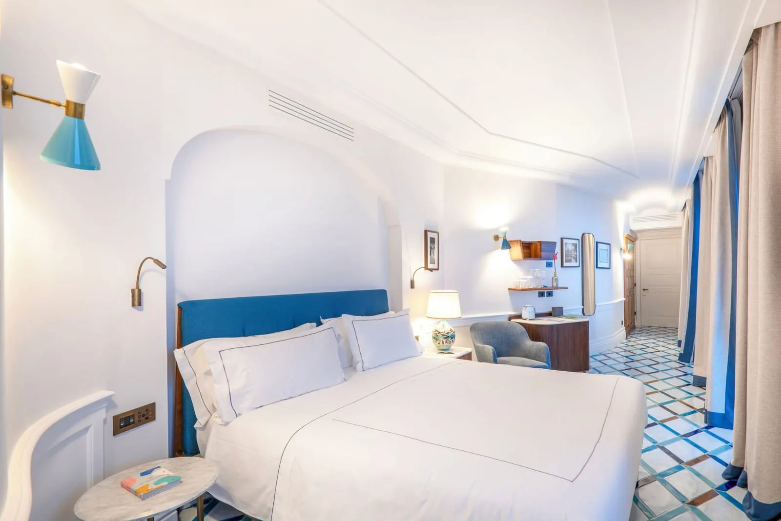 Superior Room at Borgo Santandrea: a double bed with a blue headboard, an armchair and a desk on a blue and white tiled floor.