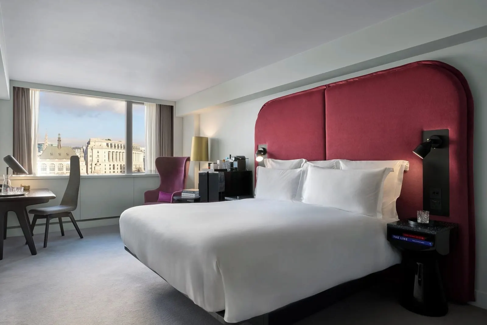 Riverview Deluxe Room at Sea Containers London: the bed with a red headboard, a desk and a window onto the buildings opposite