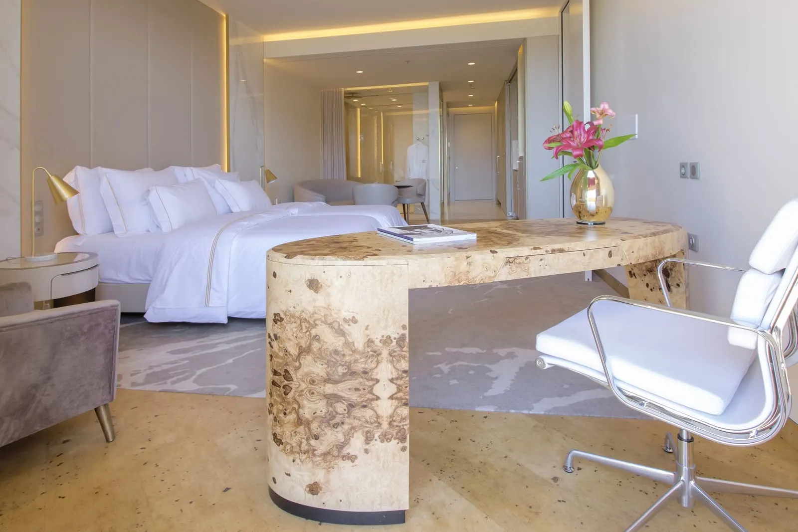 Superior Ocean Room at Savoy Palace: a king bed beside a curved burr-wood desk and white chair, with a sitting area and a glass-walled bathroom behind