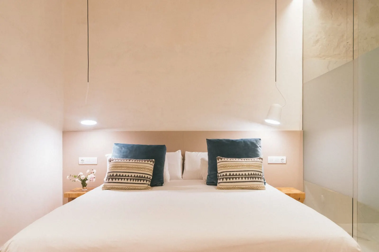 Comfort Economy Interior at Hotel Veintiuno: a double bed with blue velvet and patterned cushions under two white pendant lamps, beside a frosted glass bathroom partition