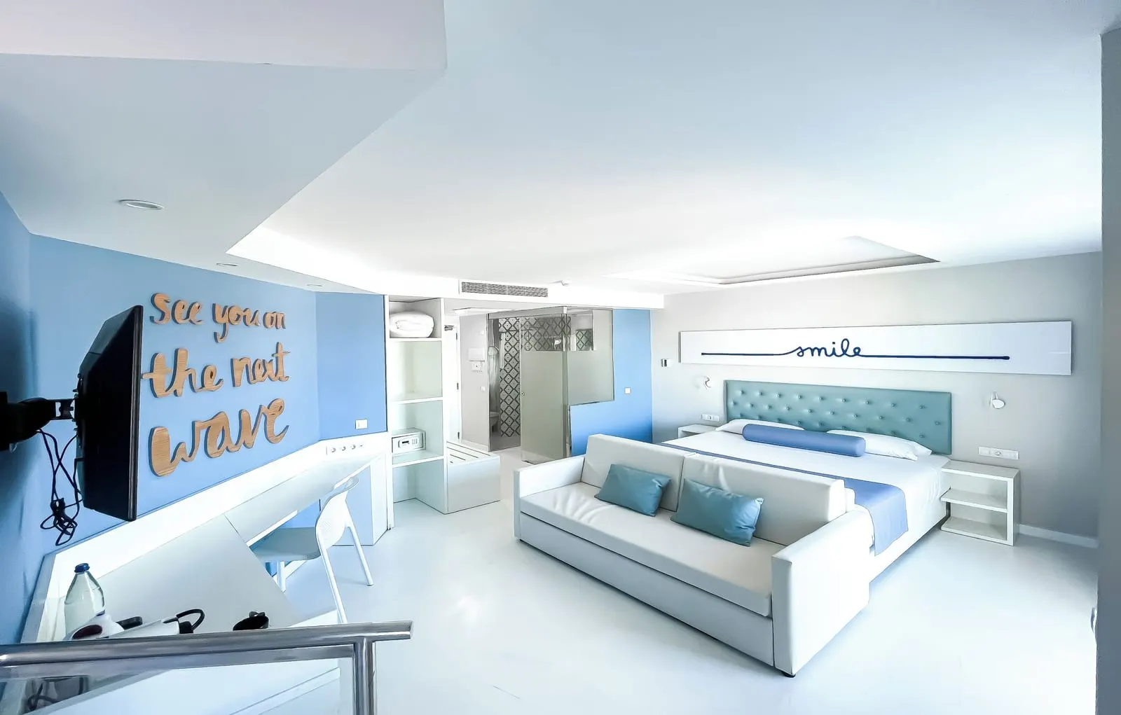 Sky Suite（Corralejo Surfing Colors Hotel & Apartments）：パッド入りヘッドボードのダブルベッドと、その手前のソファベッド、デスク、壁掛けテレビ