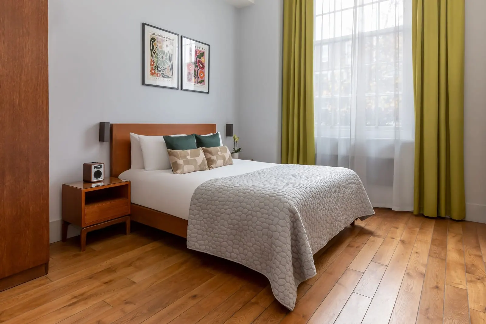 One Bedroom Suite at Town Hall Hotel: the bed with a wooden headboard beside a tall window with olive curtains