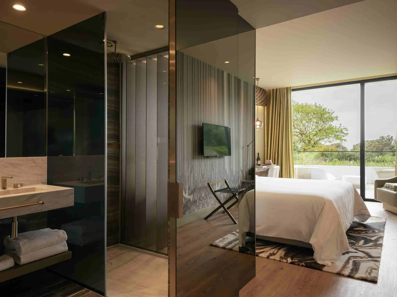 Onice Garden View Terrace Room at Vila Foz: the glass-walled bathroom and the bed by a window onto trees