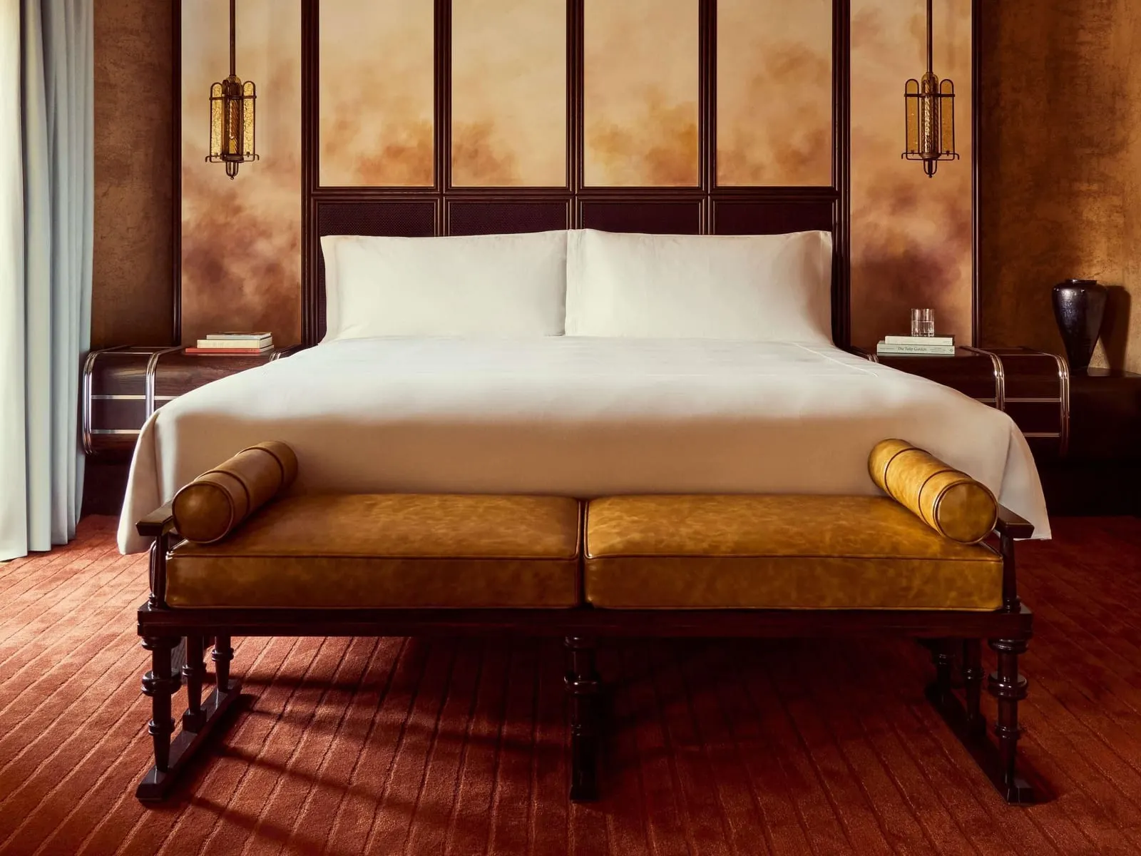 Suite at Orient Express La Minerva: the bed with a leather bench at its foot, between two bedside tables and brass lanterns