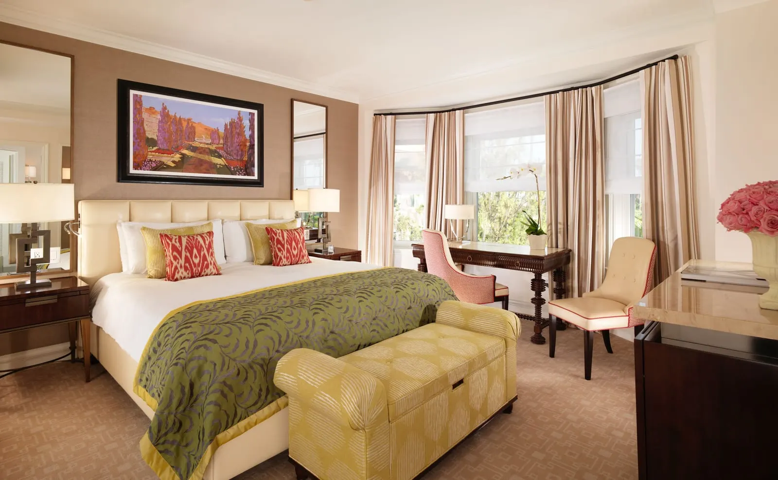 Superior Room at The Beverly Hills Hotel: a bed with a quilted cream headboard, a green leaf-patterned runner and a yellow upholstered bench, and a writing desk with two chairs in a curtained bay window
