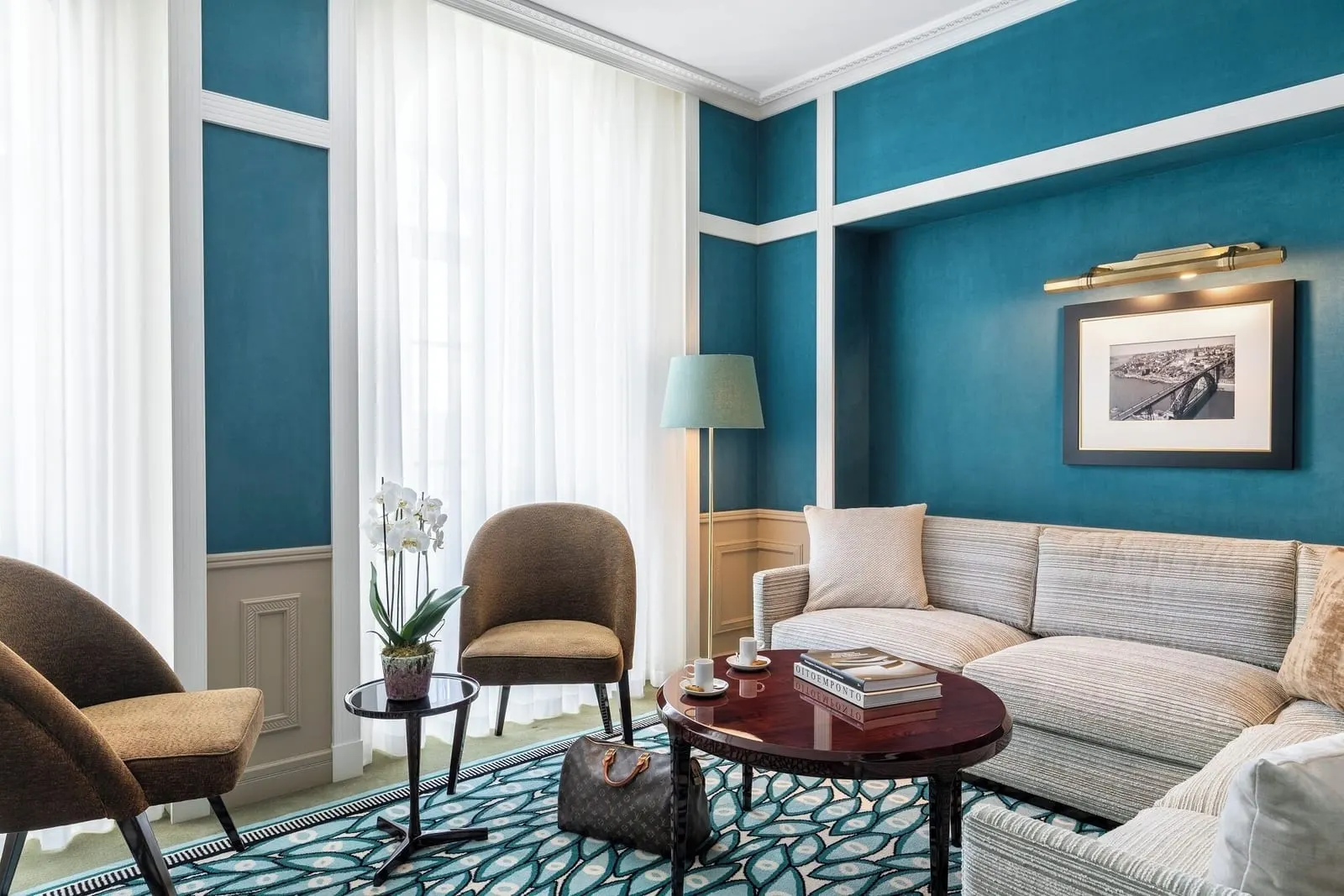 Avenida Suite living room at The One Monumental Palace: a corner sofa, a round table and two chairs by tall windows