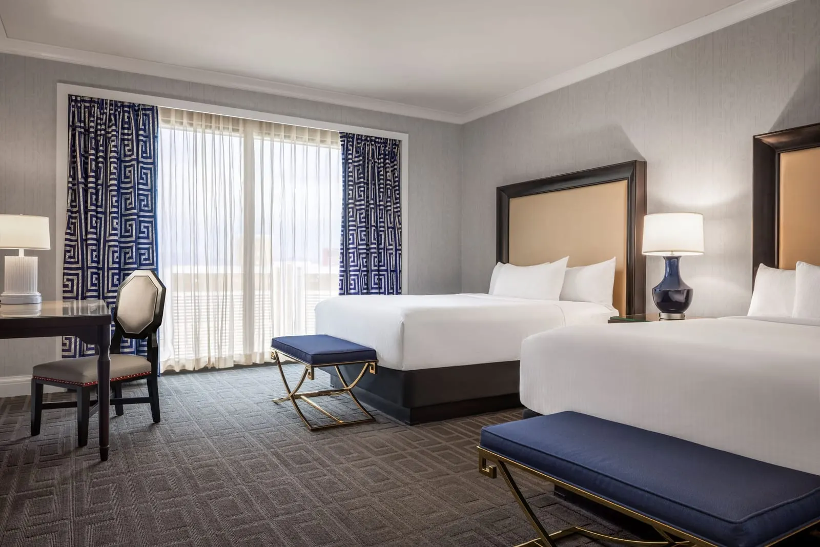 Palace Pool View Room im Caesars Palace: zwei Queensize-Betten mit blauen Bänken am Fußende und ein Schreibtisch an einem Fenster mit gemusterten Vorhängen