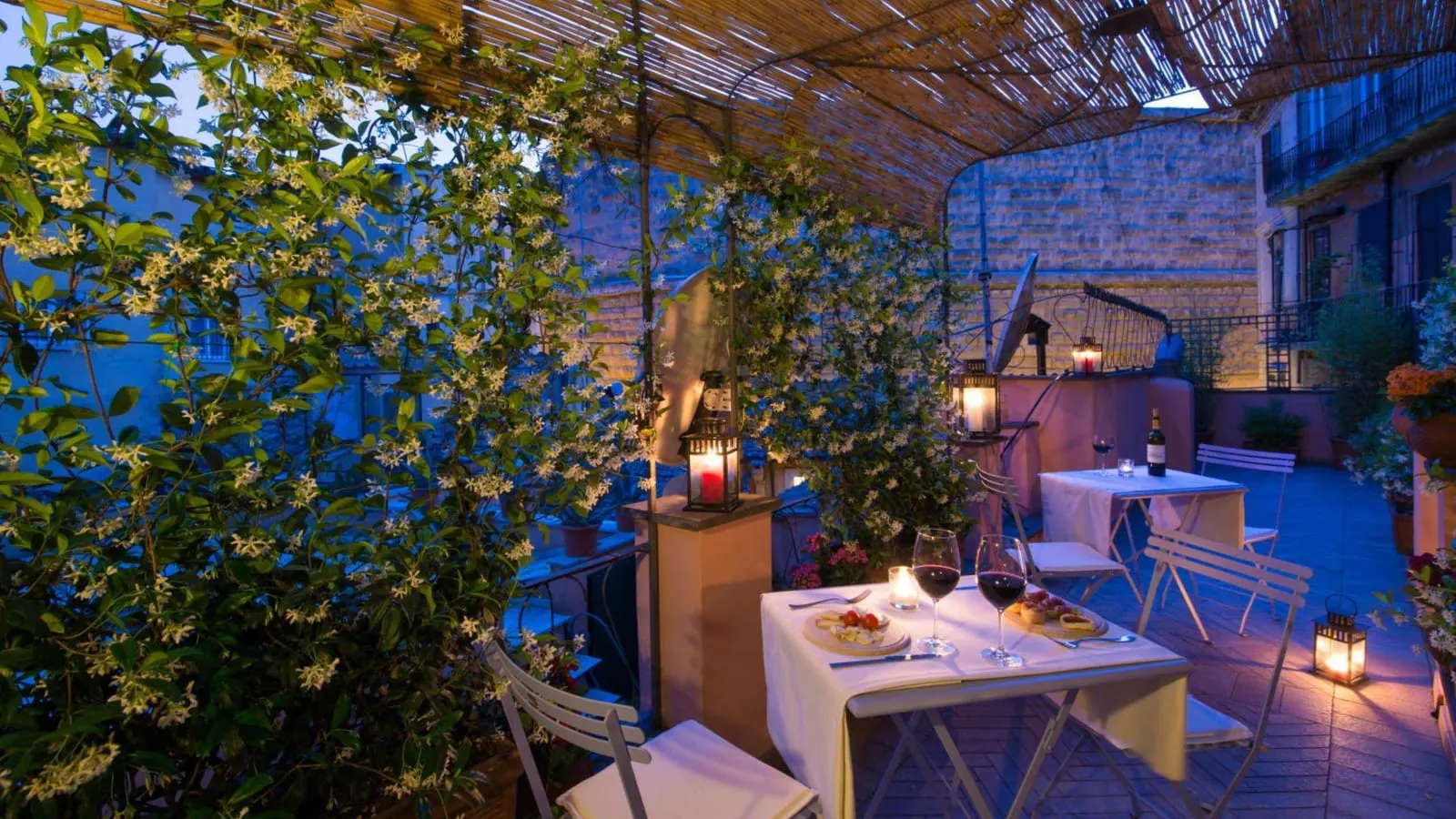 Two Bedroom Apartment at The Inn at the Roman Forum: the terrace at dusk, tables and lanterns among climbing plants