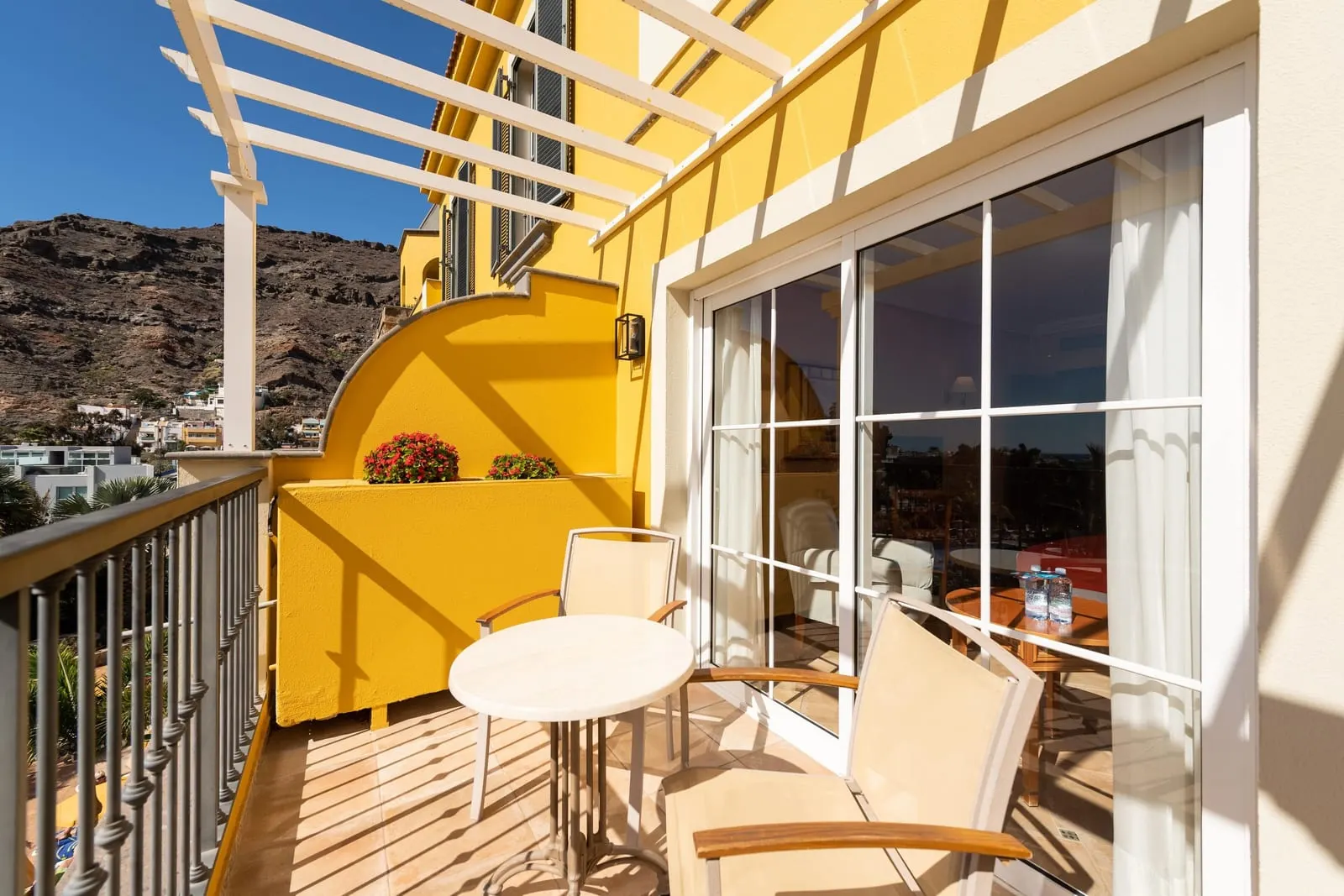 Family Room at Hotel Cordial Mogán Playa: a balcony with a round table and two chairs under a pergola, beside sliding glass doors to the room