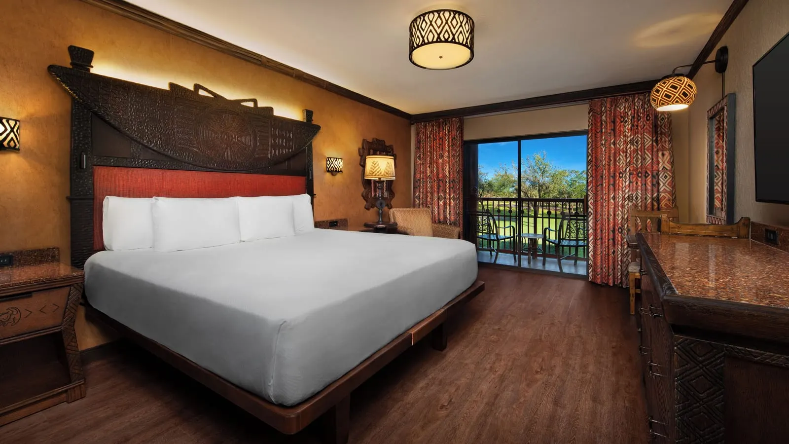 Resort View King Bed room at Disney's Animal Kingdom Lodge: a king bed with a carved wooden headboard, an armchair, a chest of drawers and a glass door onto the balcony