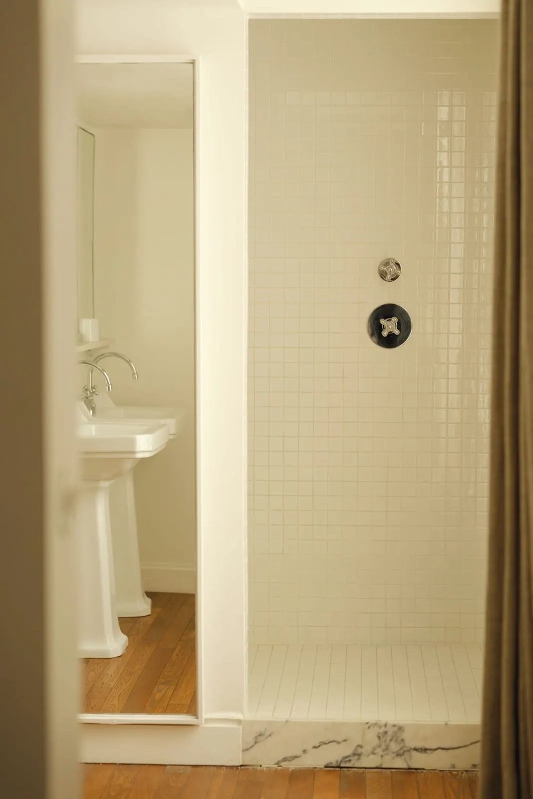 Pigalle 21 at Le Pigalle: a white-tiled walk-in shower with a marble sill, beside two pedestal washbasins