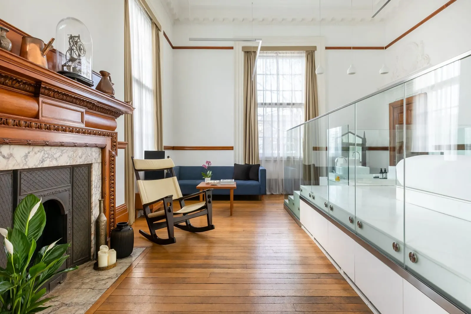 Signature Junior Suite at Town Hall Hotel: a carved wooden fireplace, a rocking chair, tall windows and a glass partition
