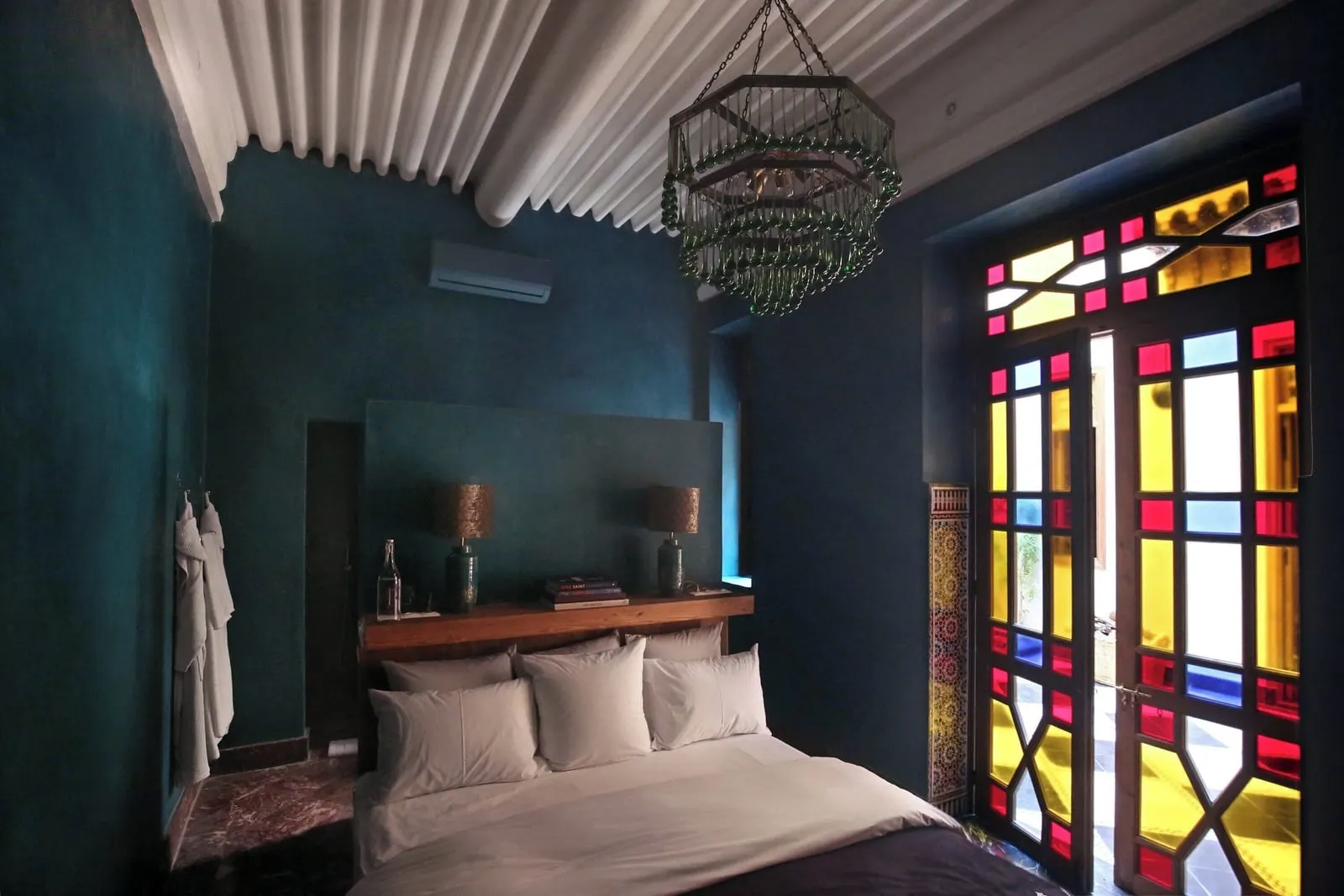 Small Room at El Fenn: a double bed against a deep blue wall beside stained-glass doors, under a painted wooden ceiling
