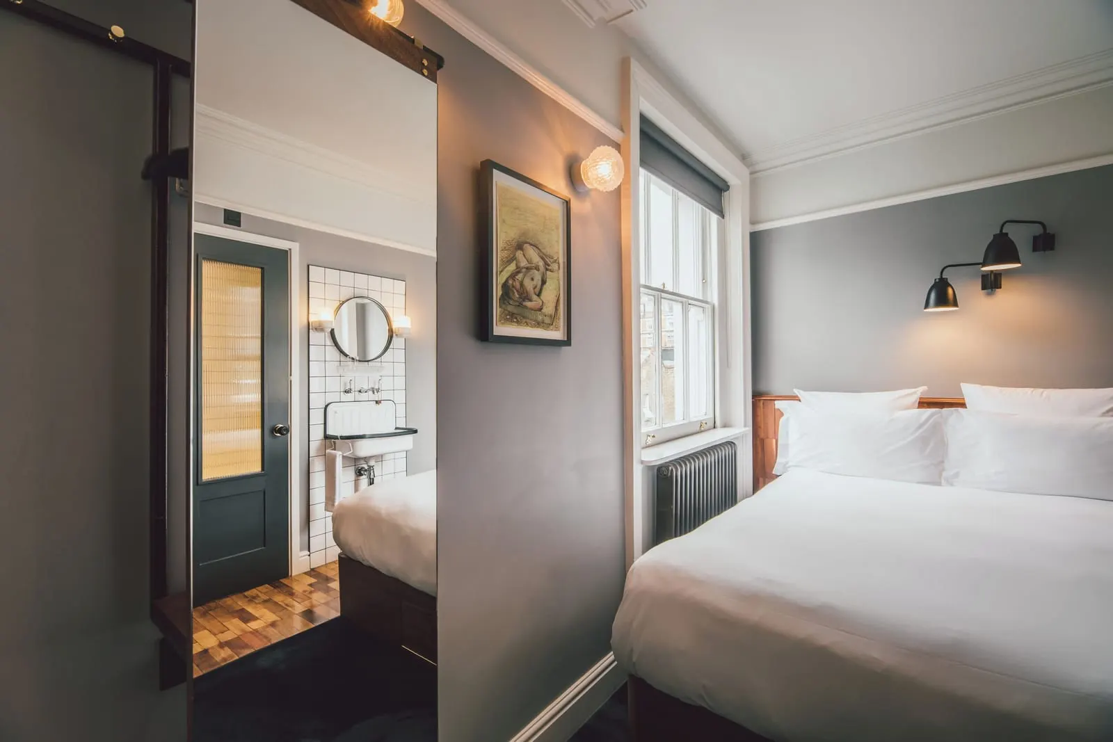 Snug at The Pilgrm: the bed by a sash window, with the bathroom door open beside it