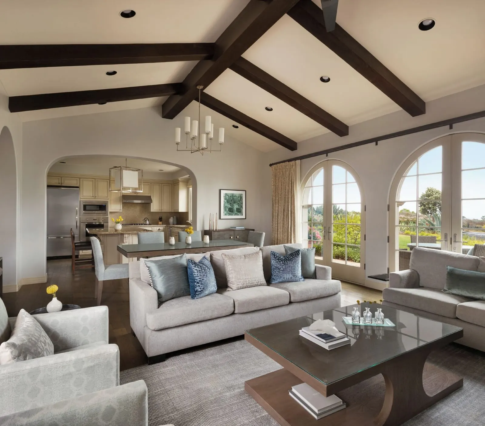 Three-Bedroom Resort Villa at Terranea Resort: an open living room with grey sofas under a vaulted beamed ceiling, with a kitchen through the arch and arched glass doors