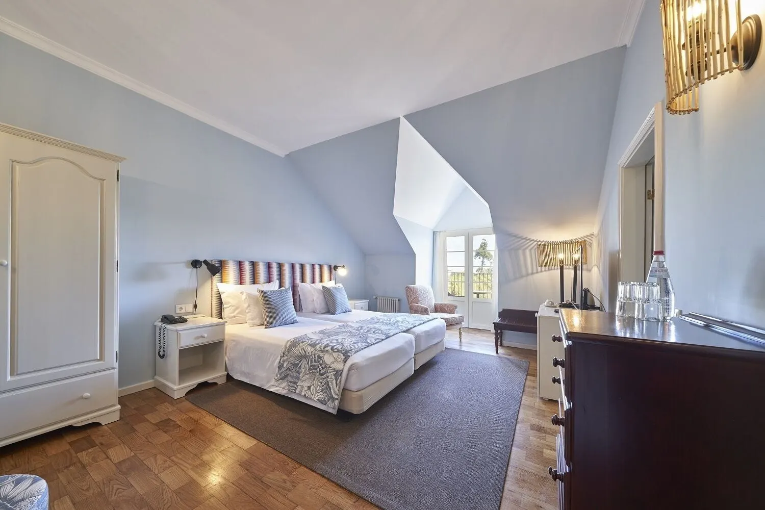Twin Vineyards im Hotel Quinta do Furão: zwei als Doppelbett bezogene Einzelbetten in einem hellblauen Dachzimmer mit schräger Decke, einem weißen Kleiderschrank, Parkettboden und einer verglasten Tür am Ende