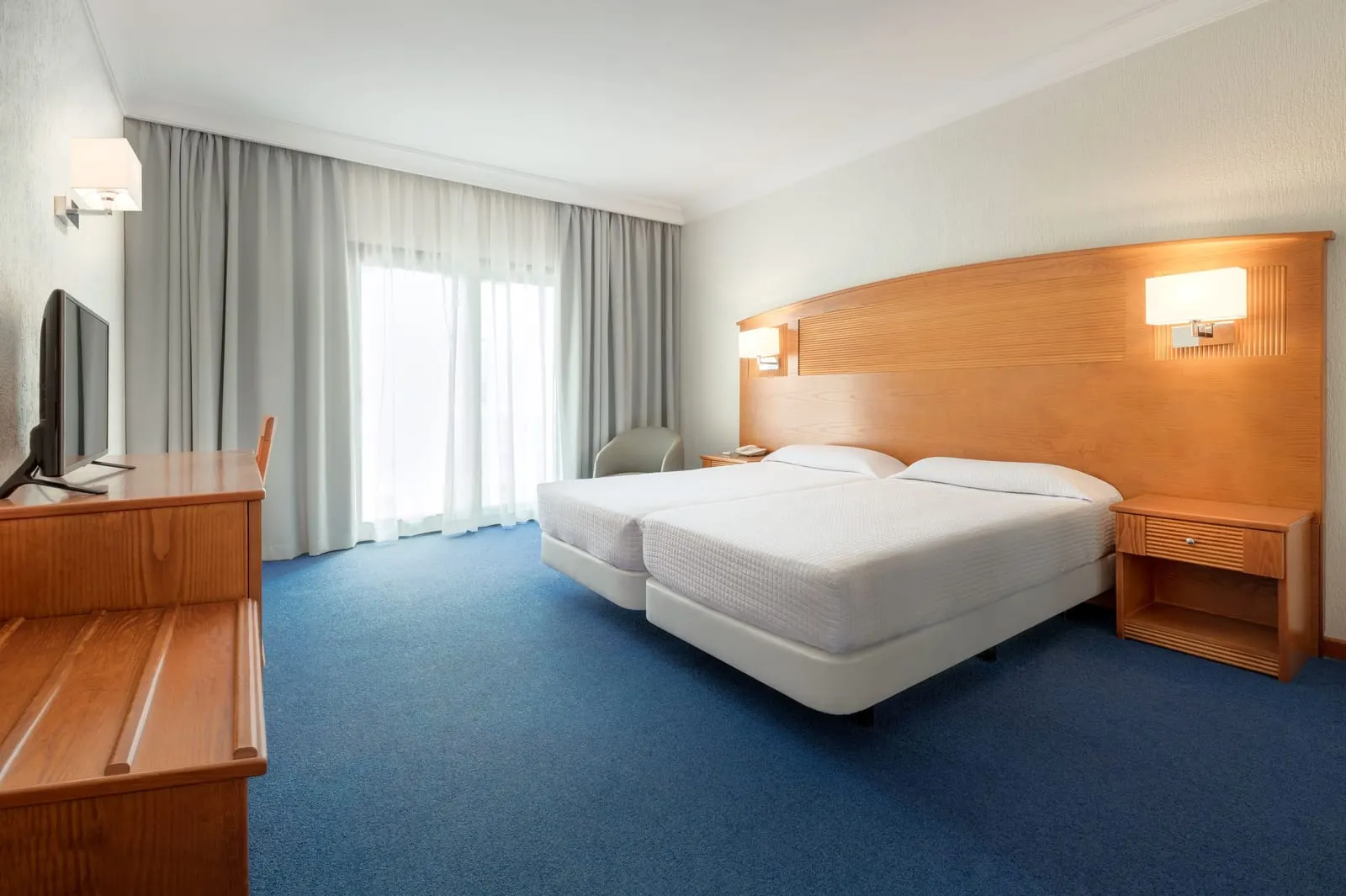 Double Standard at Hotel Lancelot: two beds pushed together under a wooden headboard, with a desk and a television on the left and a window with curtains