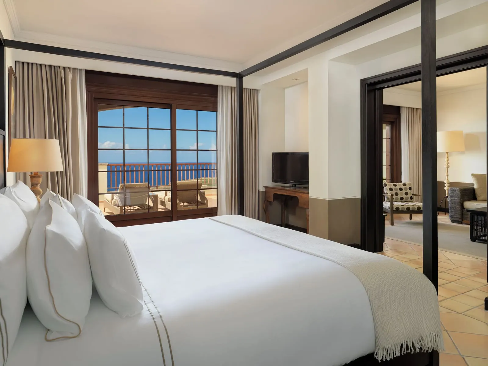 Suite Sea View With Whirlpool at Hacienda del Conde: a four-poster bed, a window onto the sea and the living room beyond