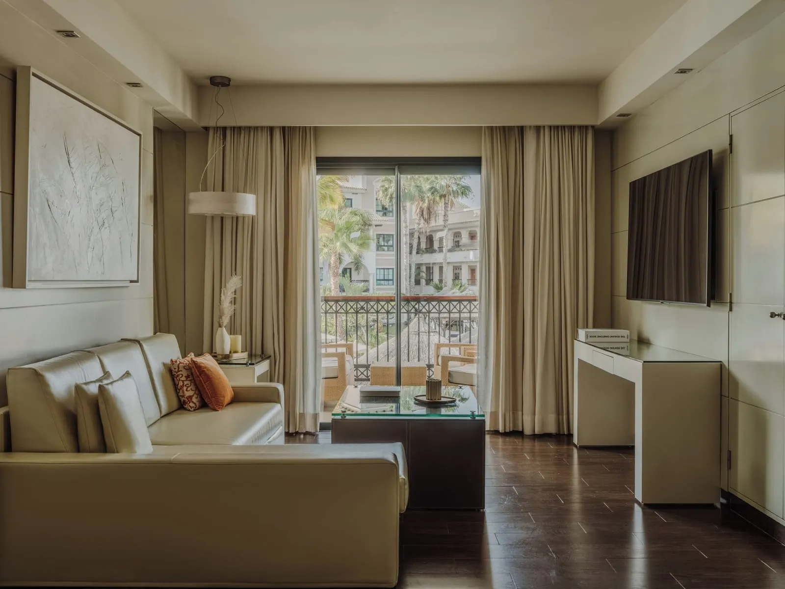 Suite at Gran Meliá Palacio de Isora: the living room, a cream sofa and a balcony door onto palms