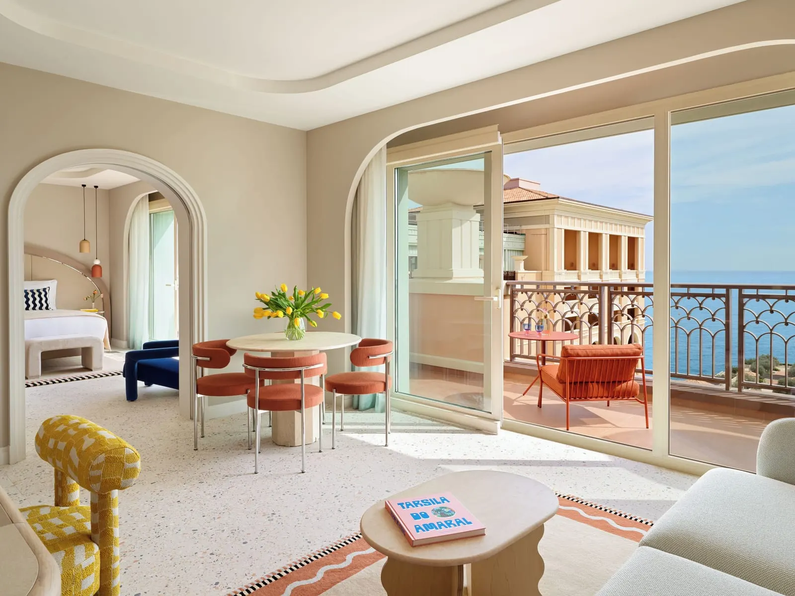Suite with sea view at Monte-Carlo Bay Hotel & Resort: a round dining table by glass doors to the terrace, the bedroom through an arch