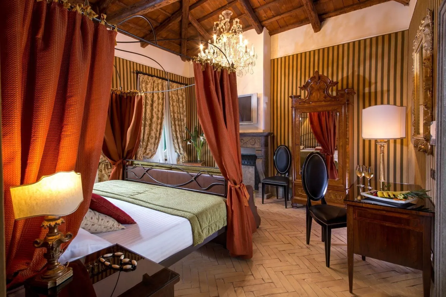 Rooftop Garden Suite at The Inn at the Roman Forum: a canopy bed with red curtains under a beamed ceiling, and a desk