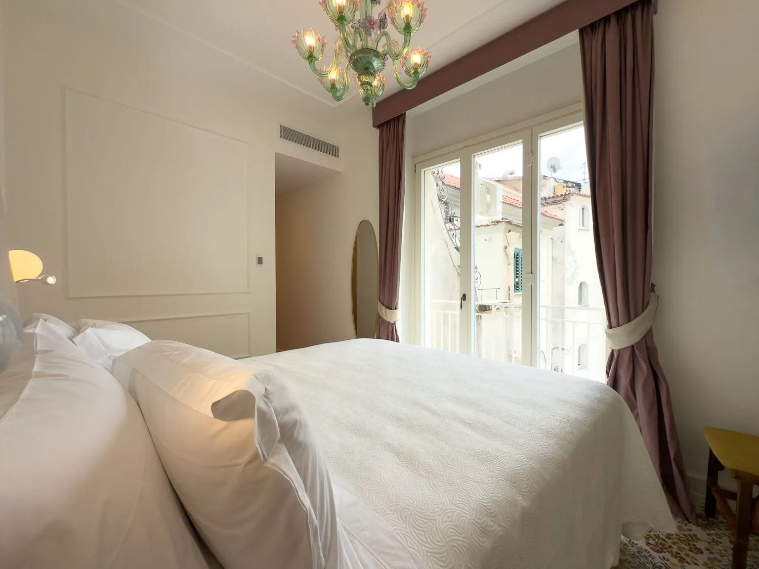 Dependance Apartment（Casa Marina Riviera、Hotel Marina Rivieraの別館）：ムラーノガラスのシャンデリアの下のダブルベッドと、屋根並みを見渡すバルコニーへのフランス窓