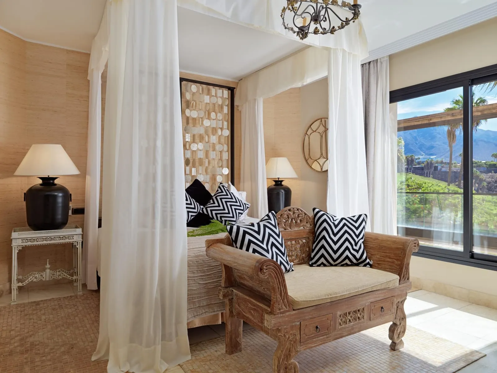 Princess Villa at Royal Garden Villas: a four-poster bed, a carved daybed and a window onto palms and hills