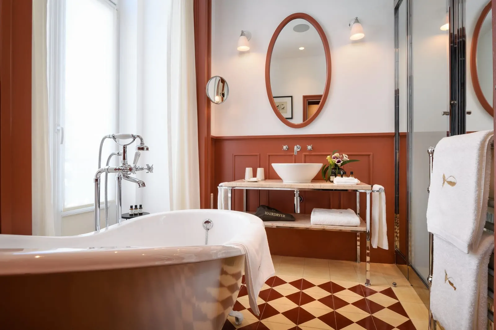 Prestige Chiado bathroom at Bairro Alto Hotel: a freestanding bath by the window, a basin stand and an oval mirror
