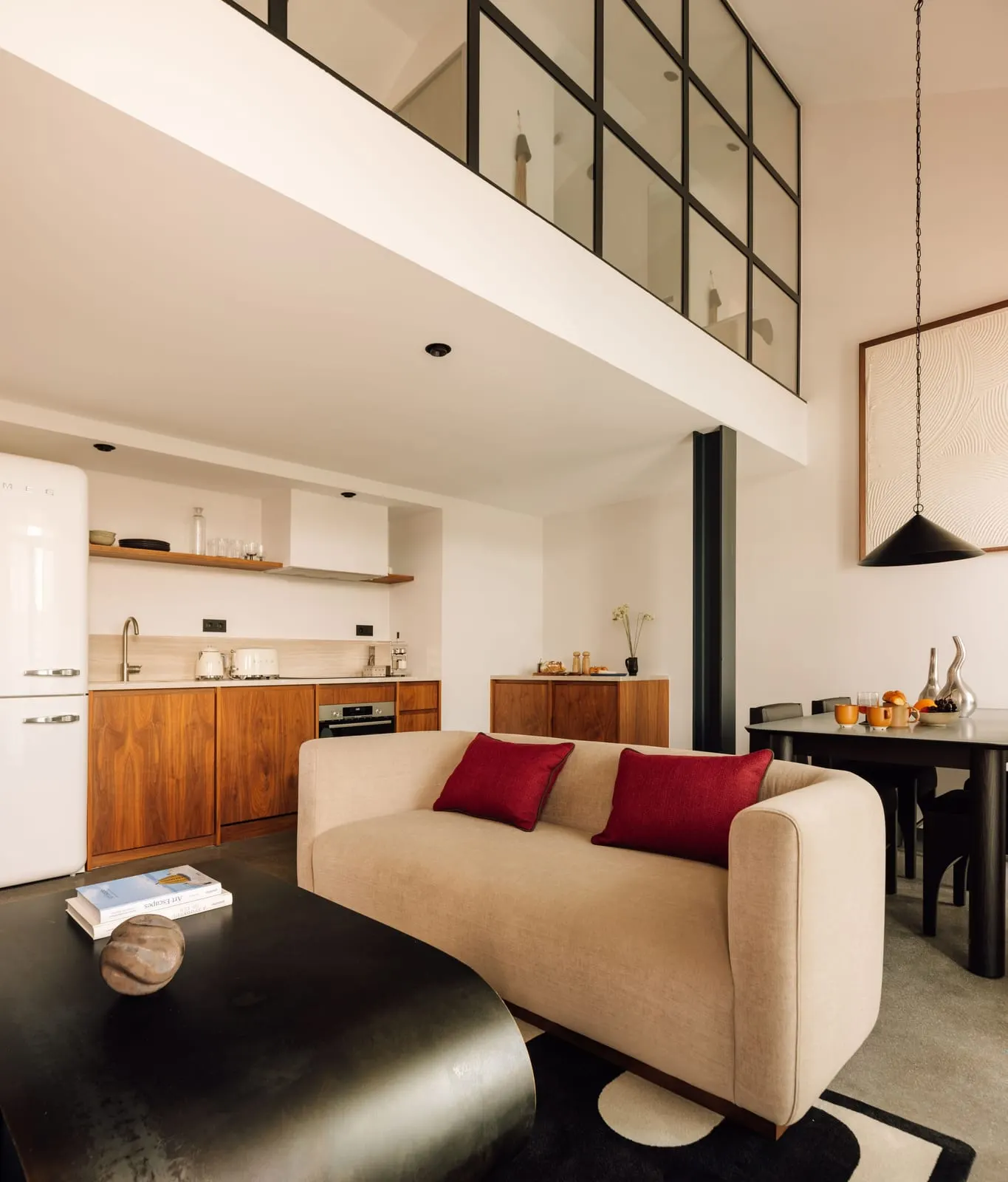 One Bedroom Duplex Suite at The Rebello: a sofa, the kitchen and a dining table below the glazed upper floor