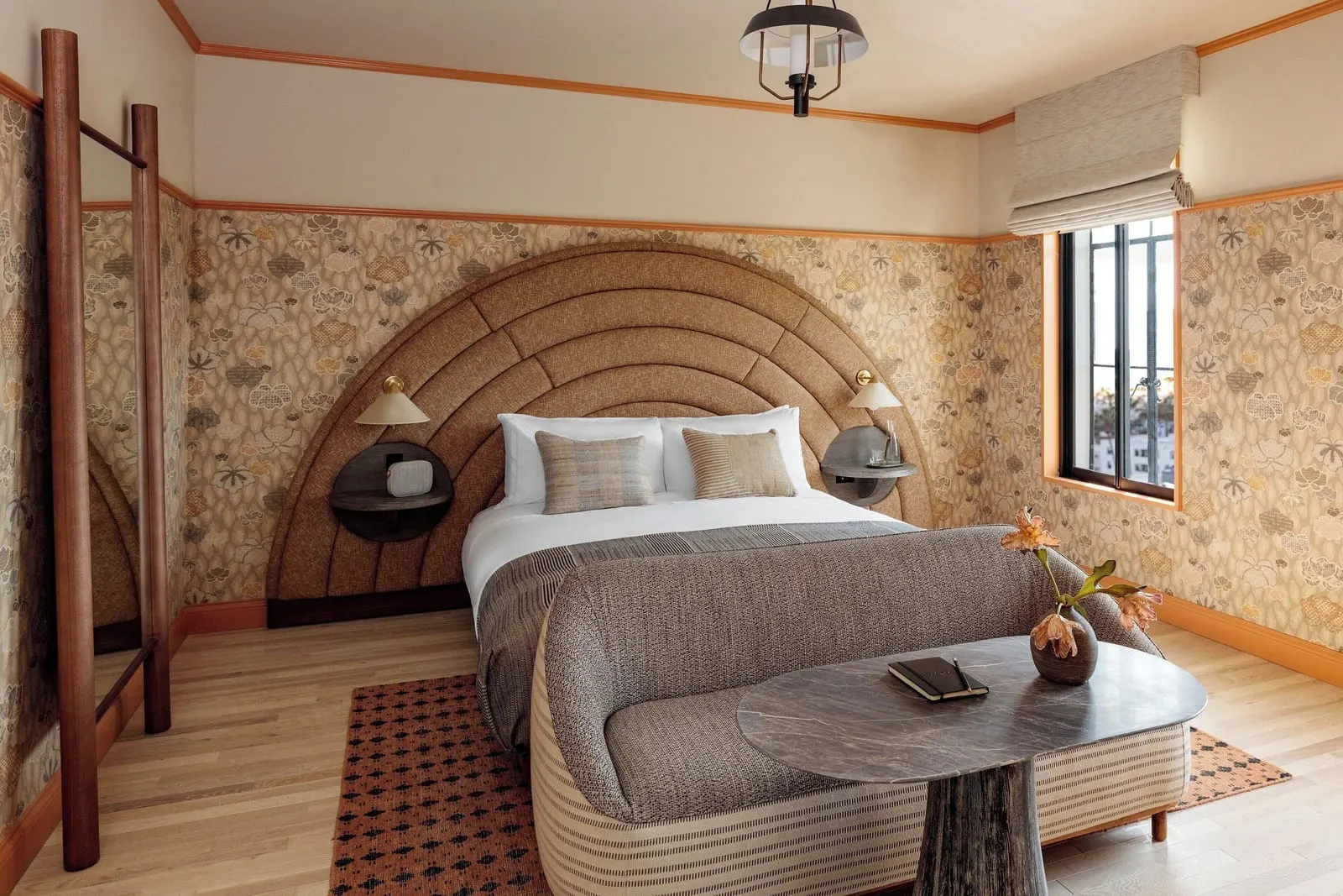 Landmark Garden Terrace im Santa Monica Proper Hotel: ein Bett mit einem bogenförmigen Kopfteil zwischen zwei runden Nachttischregalen, mit einem hohen Spiegel, einer Deckenlaterne und einem Fenster mit Raffrollo