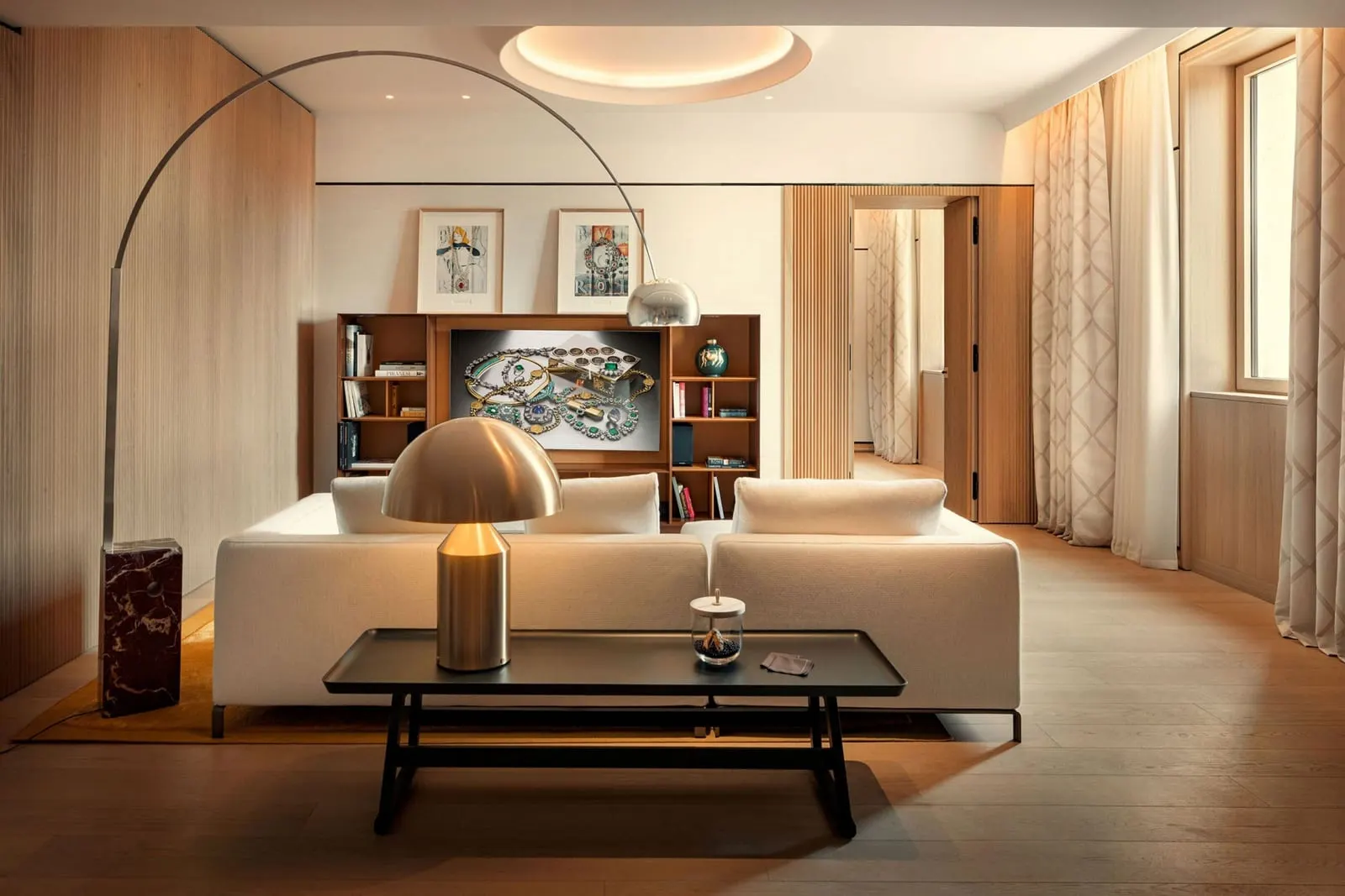 Deluxe Suite at Bvlgari Hotel Roma: the living room with a white sofa, an arc lamp and a lit bookcase