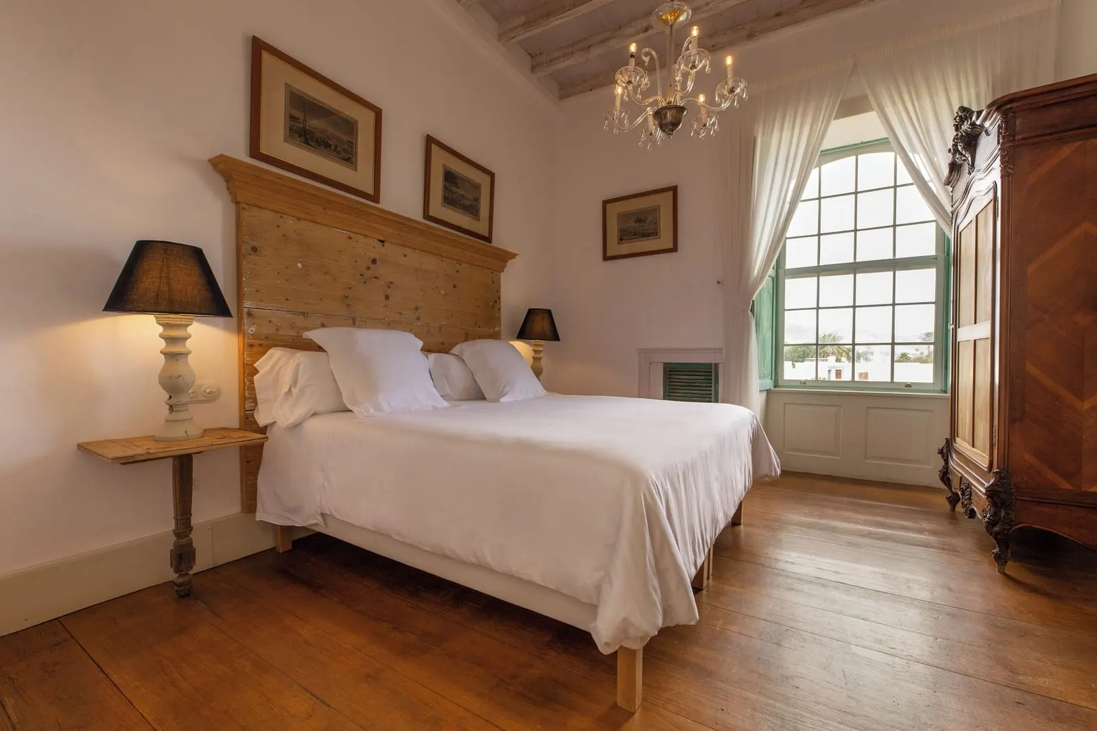 Room Nº8. Double en La Casa de los Naranjos: una cama doble con cabecero tallado y una lámpara de araña junto a una ventana en arco