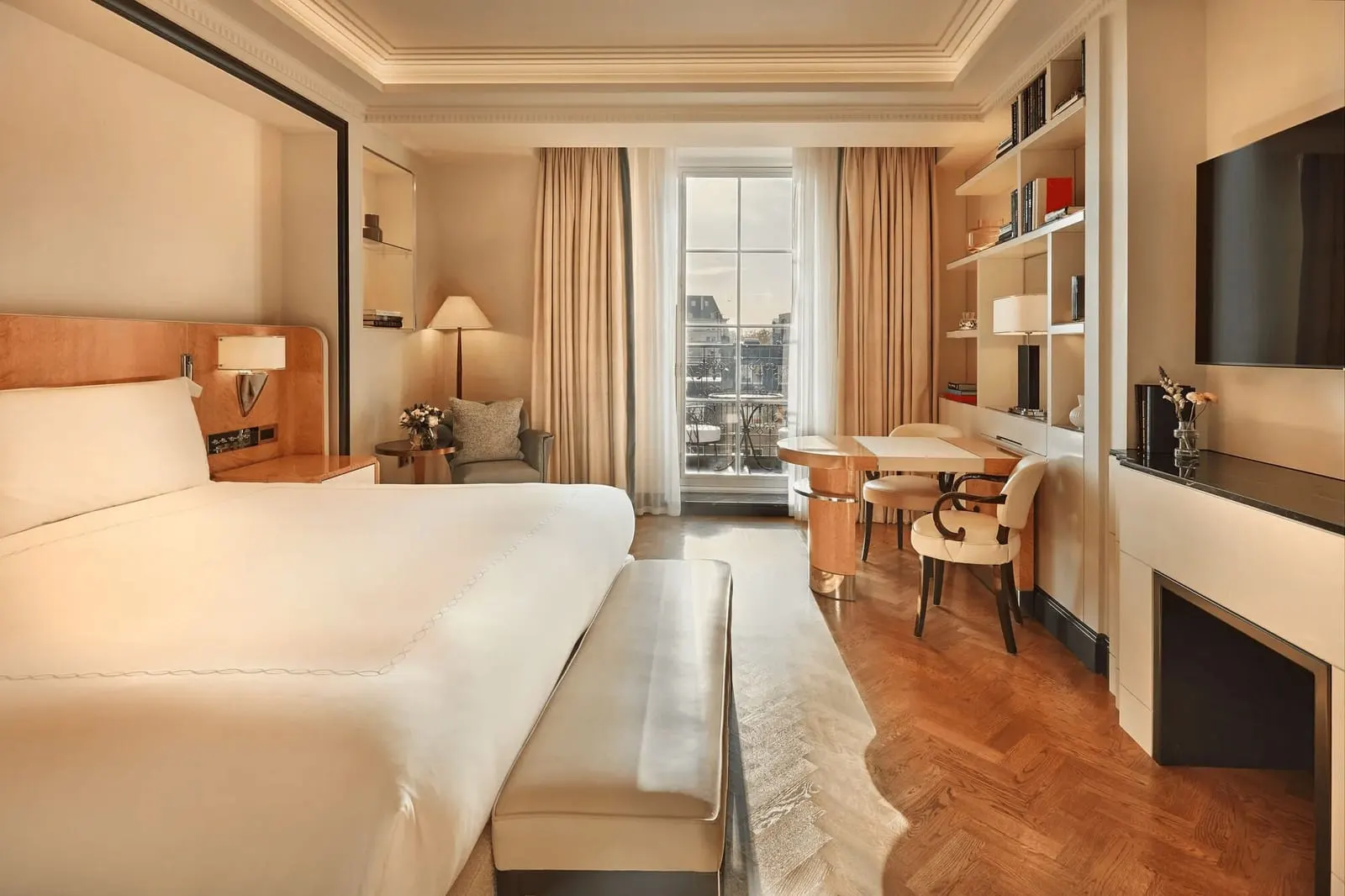 Claridge's Balcony Room at Claridge's: the bed, a table with two chairs by the window, shelves and a television