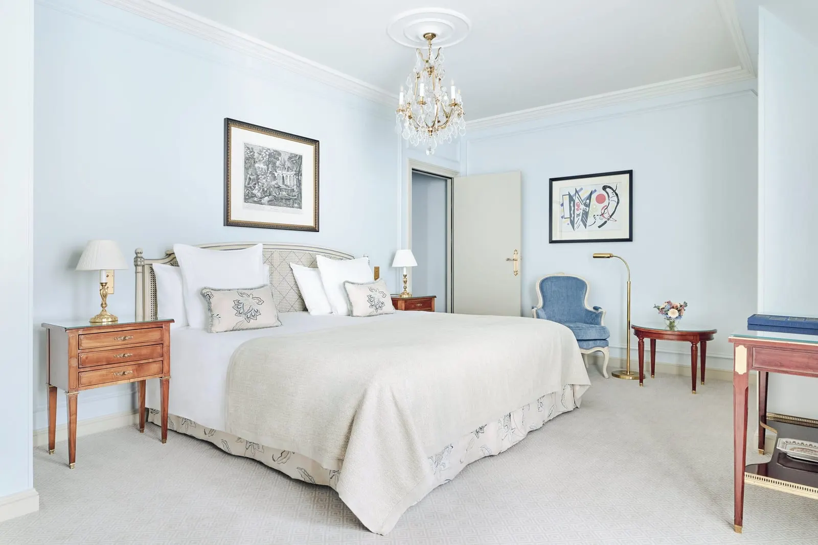 Prestige Room with balcony at Le Bristol Paris: a bed with a cream cover, a blue armchair and a small round table against pale blue walls hung with prints