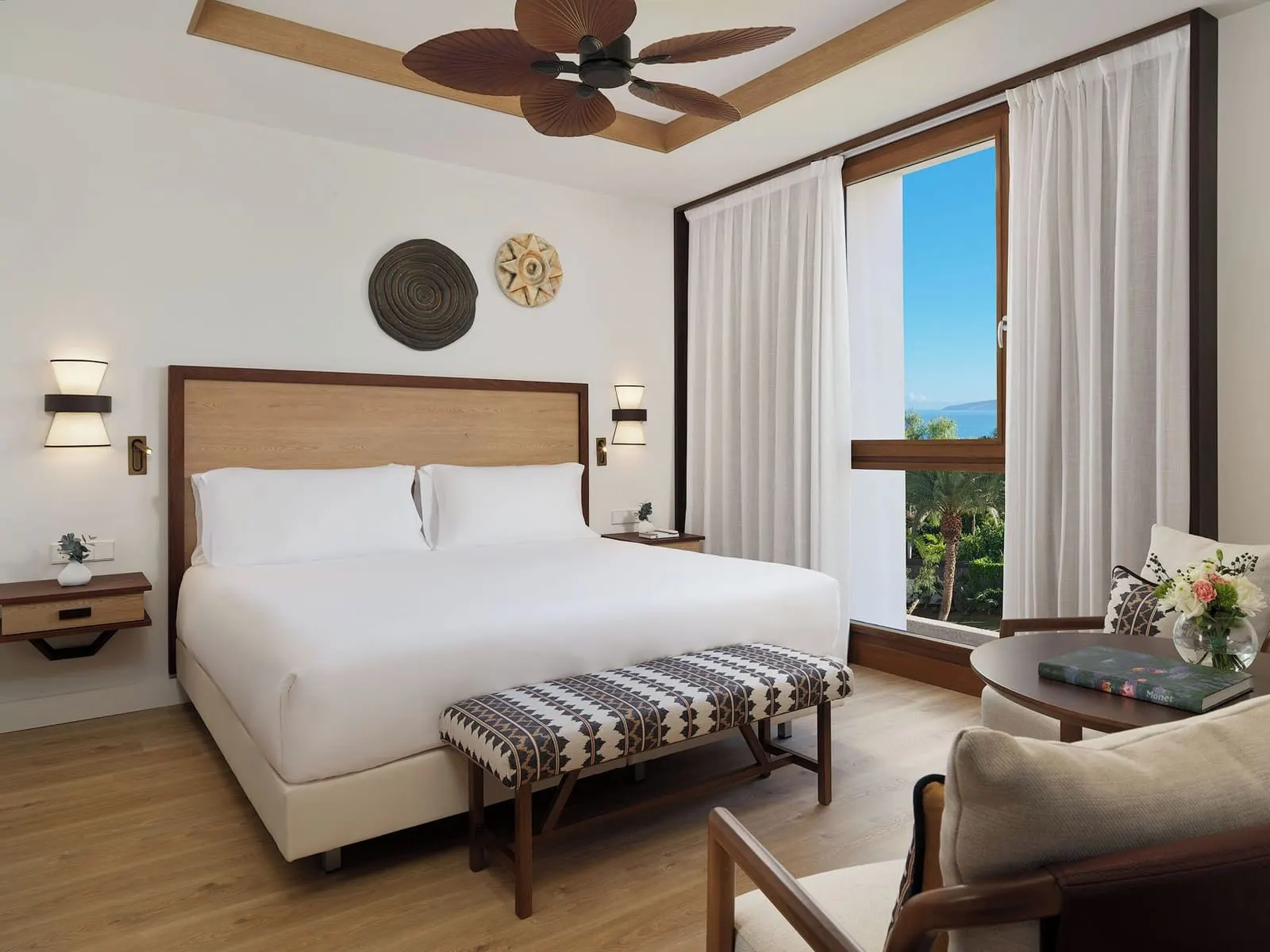 Double Deluxe Room Panoramic View at Gran Hotel Taoro: the bed, a bench, an armchair and a window onto palms and the sea