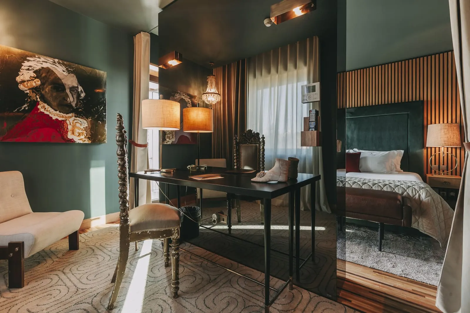 Deluxe Suite at Torel Avantgarde: a desk with a carved chair, a sofa and a large portrait, with the bed area beyond