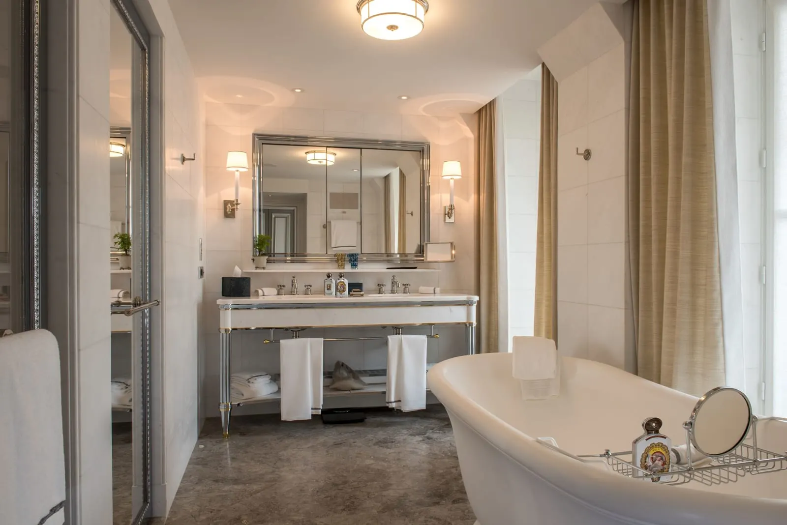 Grand Premier Room at Hôtel de Crillon, A Rosewood Hotel: the bathroom, with a freestanding bath by a curtained window and a double washstand under a wide mirror