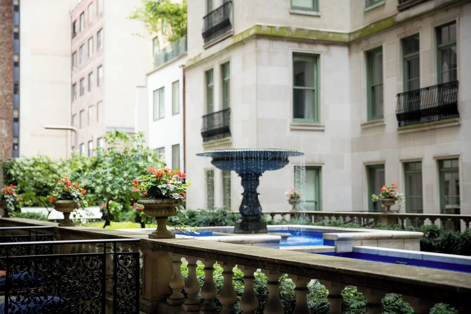 Terrace Room King at The Plaza: the landscaped courtyard seen over a stone balustrade, with a fountain standing in a blue pool and flowering urns