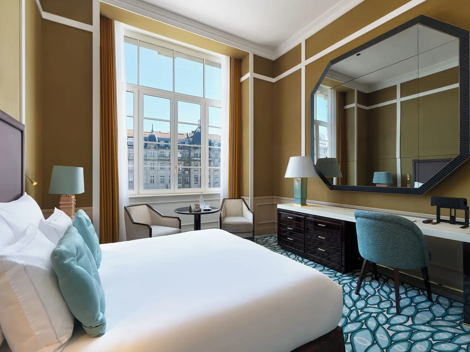 Grand Deluxe City Views room at The One Monumental Palace: the bed, a desk under an octagonal mirror and a tall window