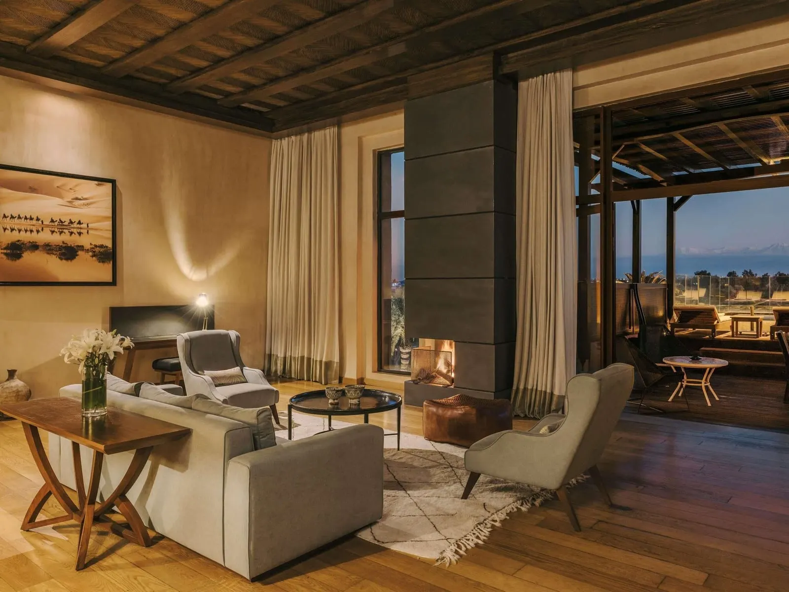 Penthouse Suite im Fairmont Royal Palm Marrakech: eine Lounge mit einem Kamin, einer Holzdecke und Türen zu einer überdachten Terrasse