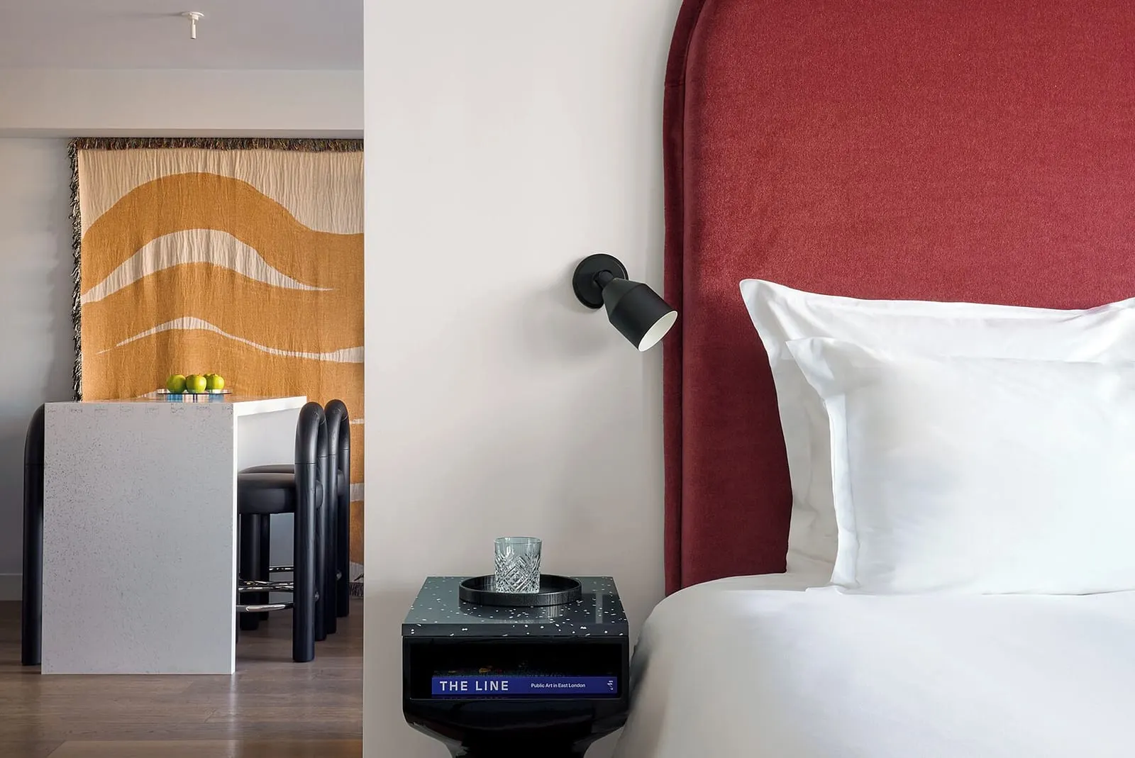 One Bedroom Suite at Sea Containers London: the bed with a red headboard, a bedside table and a white counter beyond