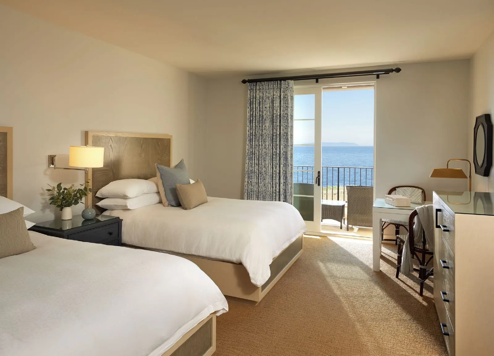 Two-Bedroom Casita, Ocean View at Terranea Resort: a bedroom with two beds, a writing desk and glass doors onto a balcony with the sea beyond