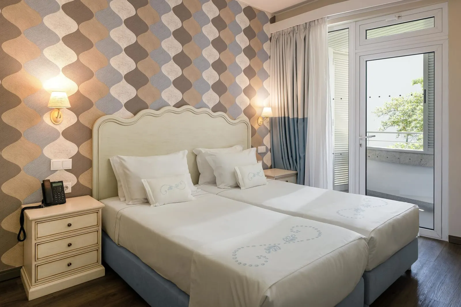 Junior Suite at Hotel Madeira: two single beds made up side by side under a padded headboard, with a glass door out to a balcony