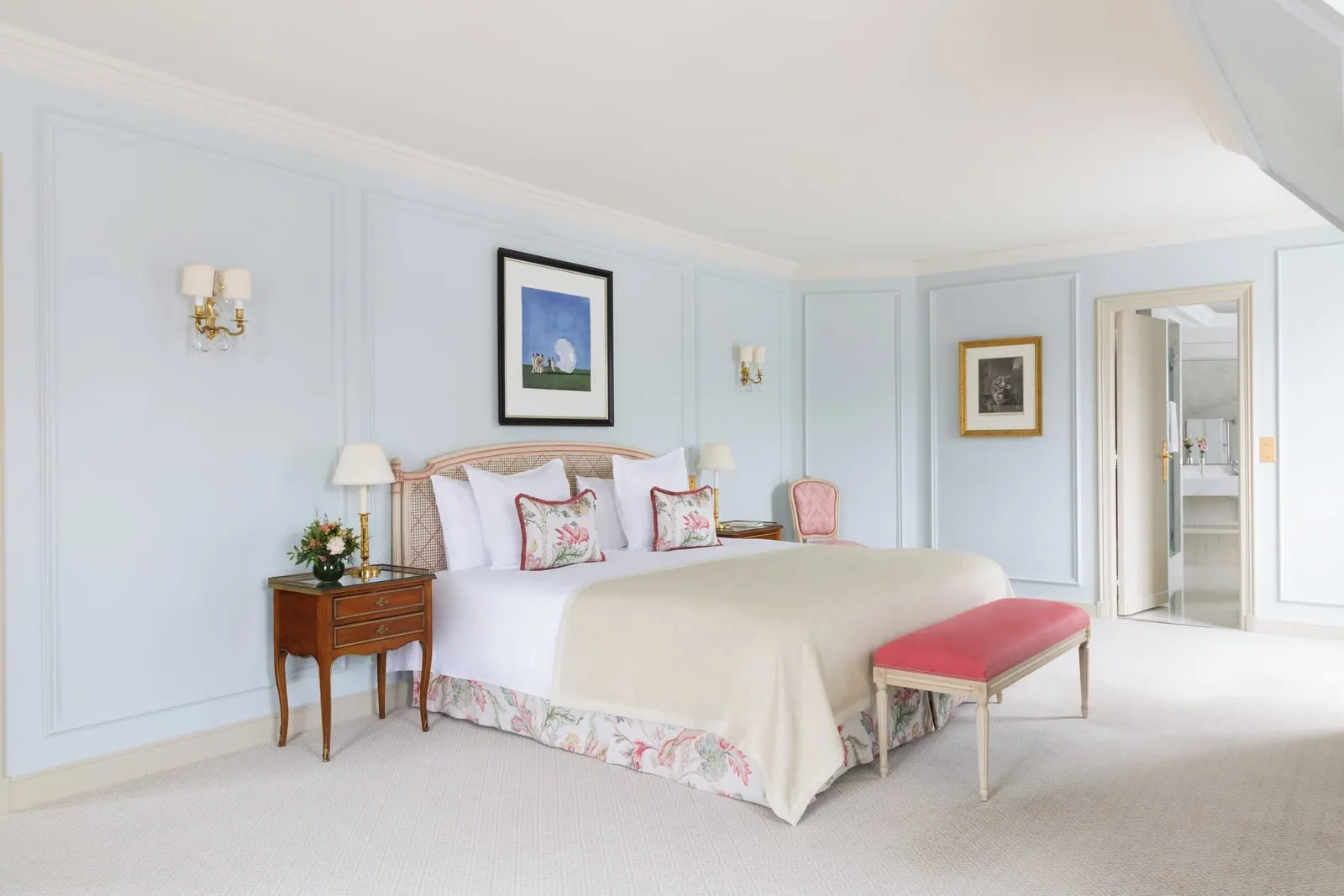 Suite Panoramique at Le Bristol Paris: a bed with a cream throw and a pink bench against pale blue panelled walls with brass wall lights